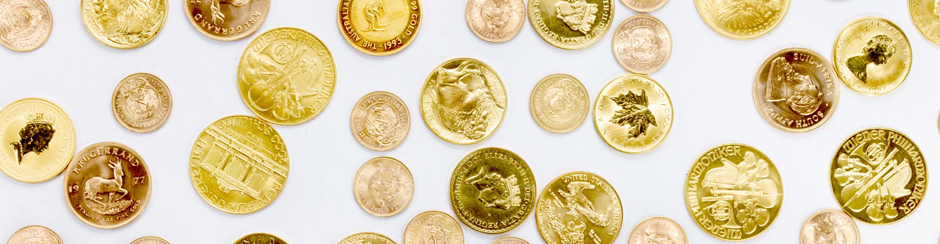 Verschiedene Goldanlagemünzen unter anderem Krügerrand, Maple Leaf und Golden Nugget